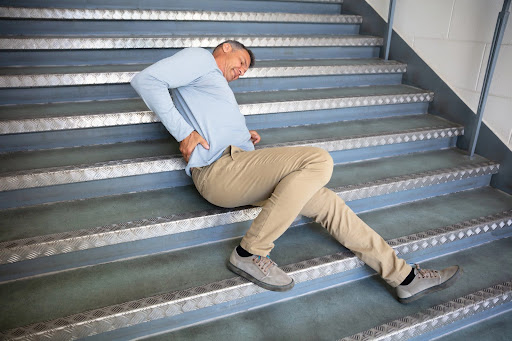 Zavodnick & Lasky Personal Injury Lawyers | Personal Injury Lawyer New Castle County, DE A man clutching his lower back, sprawled on steps capped with galvanized metal; personal injuries from slip and fall accidents can cause long-lasting pain and suffering.