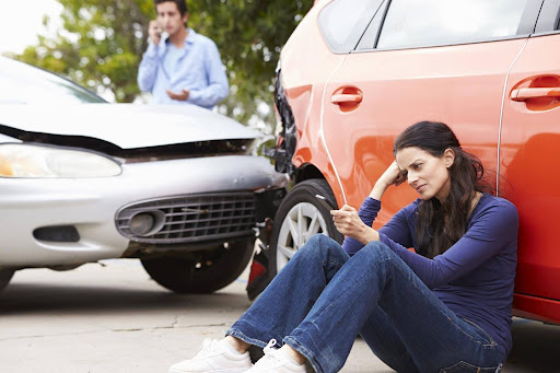 A woman and a man beside their vehicles after a car accident. A woman and a man beside their vehicles after a car accident.