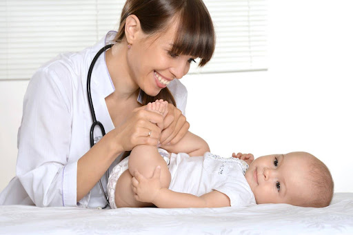A smiling doctor examines a baby for possible birth injuries, a form of medical malpractice. A smiling doctor examines a baby for possible birth injuries, a form of medical malpractice.