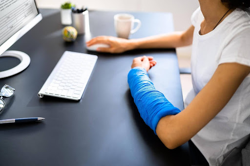 Zavodnick & Lasky Personal Injury Lawyers | Do Most Delaware Slip And Fall Cases Settle Out Of Court? A woman with a blue arm cast filing online forms to settle out of court after a slip and fall injury.