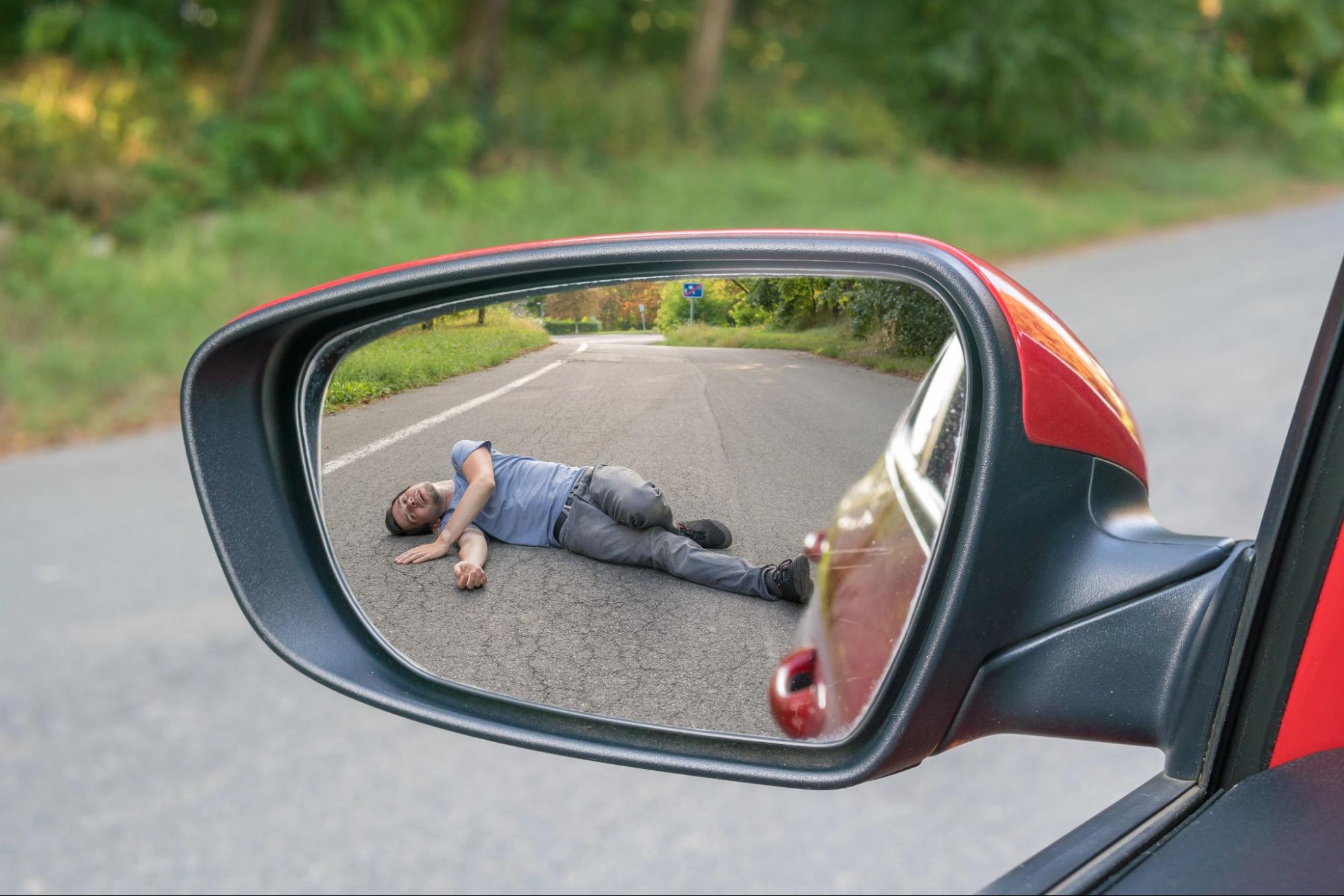 image2 A sideview mirror captures an injured man lying on the road as a red car drives away.